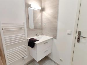 a white bathroom with a sink and a mirror at Le Nid du Pont Neuf in Pamiers