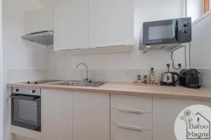 a white kitchen with a sink and a microwave at Buzz à Disneyland Paris in Magny-le-Hongre +2 photos