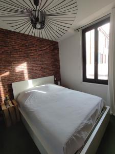 a bedroom with a large white bed with a brick wall at Ô petit cocon in Albi