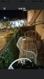 Dos bancos blancos sentados en un balcón por la noche en Casa Lella, en Policoro
