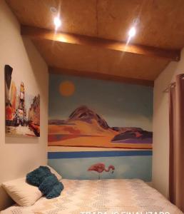 a bedroom with a bed with a painting on the wall at Desert Wings in San Pedro de Atacama