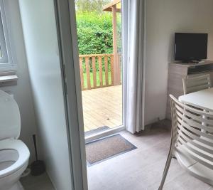 a bathroom with a toilet and a door to a deck at Mobile home 6P XL Climatisation TV WIFI parcelle XXL au calme in Ivry-la-Bataille +7 photos