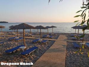 a beach with chairs and umbrellas and the ocean at Alexios Aparments in Néa Seléfkeia +27 photos