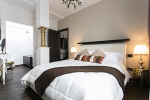 ミラノにあるアパートホテル デイ メルカンティのベッドルーム1室(白いベッド1台、白いシーツ、茶色の枕付)