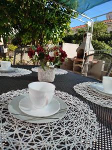 a table with cups and saucers on top of a table at Cute apartment Arba in Rab