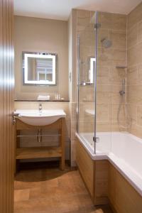 a bathroom with a tub, sink and mirror at Carden Park Hotel, Golf Resort and Spa in Tilston