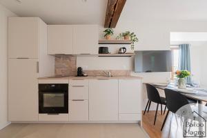 a kitchen with white cabinets and a table with chairs at Le Refuge de Bagheera à Disneyland in Magny-le-Hongre