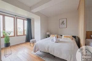 a white bedroom with a bed and a large window at Le Refuge de Bagheera à Disneyland in Magny-le-Hongre