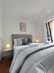 two white beds in a bedroom with a window at Garajau Views in Caniço
