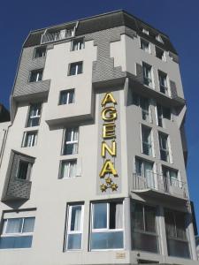 un grand bâtiment blanc avec un panneau jaune dans l'établissement Hôtel Agena, à Lourdes