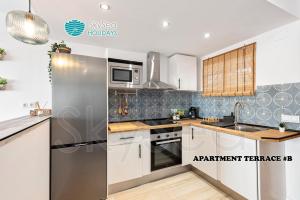 a kitchen with white cabinets and a stainless steel refrigerator at SKYSEA Benalmadena Puerto Marina in Benalmádena