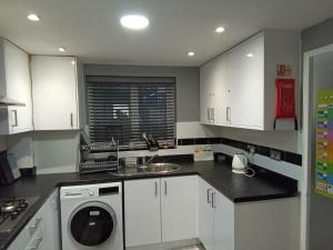 a kitchen with white cabinets and a sink and a dishwasher at Bridgewoods in Chatham