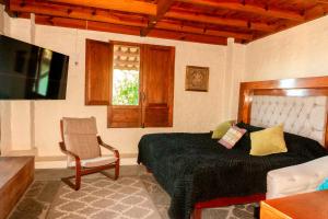 a bedroom with a bed and a chair and a window at Casa en Tapalpa Cerca del Centro in Tapalpa