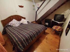 a bedroom with a bed and a tv and a staircase at Hospedaje Pensión Ely Cabaña 2 habitaciones 5 personas in Temuco