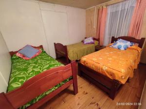 two beds sitting in a room with wooden floors at Hospedaje Pensión Ely Cabaña 2 habitaciones 5 personas in Temuco