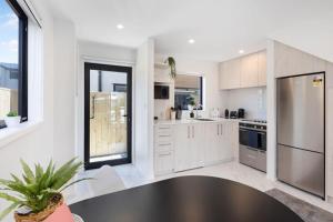 a kitchen with white cabinets and a stainless steel refrigerator at Radiant Spot on Biddle Crescent in Lower Hutt