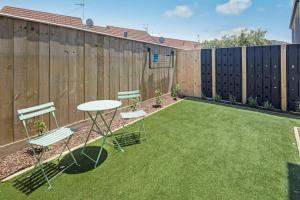 une cour avec une table, des chaises et une clôture dans l'établissement The Comfortable Biddle Cottage, à Lower Hutt
