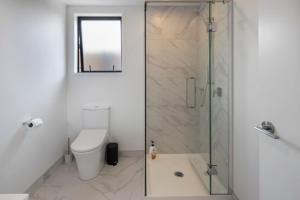 une salle de bain avec toilettes et douche en verre dans l'établissement The Comfortable Biddle Cottage, à Lower Hutt