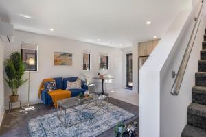 un salon avec un canapé bleu et un escalier dans l'établissement The Comfortable Biddle Cottage, à Lower Hutt