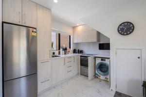 une cuisine avec des armoires blanches et une horloge au mur dans l'établissement The Comfortable Biddle Cottage, à Lower Hutt