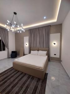 a bedroom with a large bed and a chandelier at Exquisite 1&2 Bedroom Apartment- Holi Flats Airport Residential Area in Accra