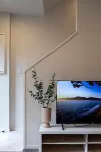 a flat screen tv sitting on a table with a plant at Groveview Oasis 1BR Retreat in Lower Hutt