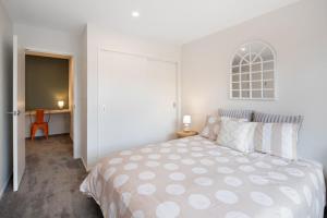 a white bedroom with a bed and a desk at Groveview Oasis 1BR Retreat in Lower Hutt