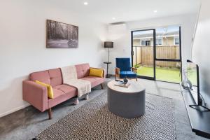 a living room with a pink couch and a table at Tranquil Stay at Rainey Grove in Lower Hutt