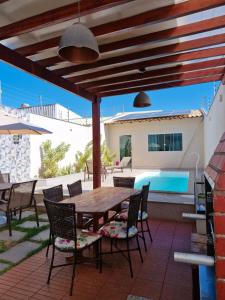 a patio with a wooden table and chairs and a pool at Ivana Imoveis - Casa com Piscina na Praia do Morro á 2 minutos da praia in Guarapari +200 photos