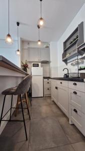 a kitchen with white cabinets and a counter with a chair at Jad Studio Mamaia Nord in Mamaia Nord