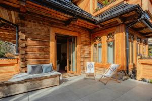 a porch of a wooden house with a bed and two chairs at Villa Vena in Zakopane