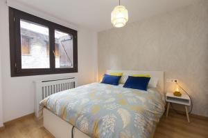 Un dormitorio con una cama con almohadas azules y una ventana. en Casa Real by BeValle, en Escarrilla