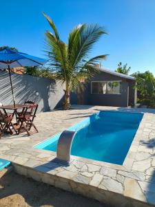 a swimming pool with a palm tree and a house at Casa com Piscina em Búzios in Buzios