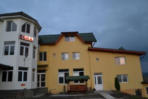 un bâtiment jaune et blanc avec un panneau sur lequel figure un panneau dans l'établissement Hostel Cora, à Haţeg