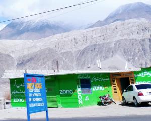 a green building with a car parked in front of it at Zia Guest House in Gilgit