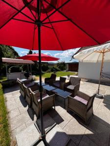 グロースシェーナウにあるFerienhaus Schwarzer Katerの赤い傘付きテーブルと椅子