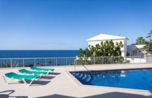 una piscina con 2 tumbonas y el océano en Atardecer 1, en Puerto de Santiago