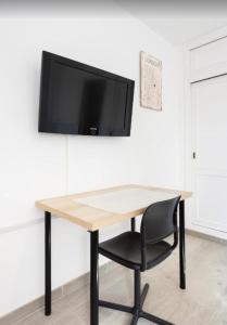 Un escritorio con una silla y un televisor en una pared. en Atardecer 1, en Puerto de Santiago