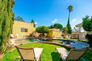 a yard with a pool and two chairs and a house at Pool Spa Games Peaceful Garden Retreat in Glendale