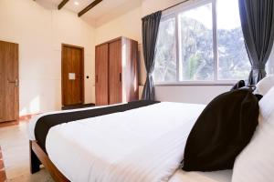 Un dormitorio con una gran cama blanca con ventana. en Collection O Dona Karen, en Goa