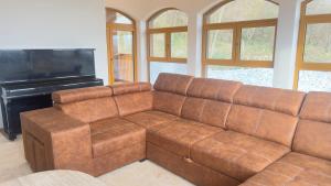 a brown couch in a living room with a piano at Villa Beelvita&Jacuzzi in Bielovce