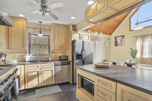 a kitchen with wooden cabinets and a stainless steel refrigerator at Hot Tub Fire Pit Game Room Family Getaway in Hedgesville
