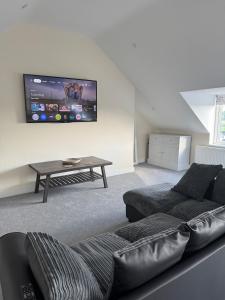 a living room with a couch and a tv on the wall at Studio Apartment with games room in Royal Wootton Bassett