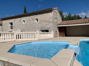 a large blue swimming pool in front of a building at Gîte Ferrari 07 Ruoms in Ruoms