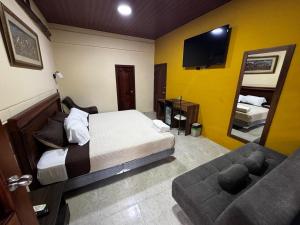 a bedroom with a bed and a couch and a tv at Salamandras Hostería & Spa in Tena