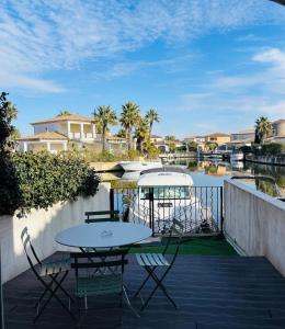 d'une terrasse avec une table, des chaises et un bateau. dans l'établissement Marina Le Paradis sur l'eau, à Aigues-Mortes