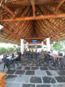 a restaurant with tables and chairs and a wooden roof at Rancho de Pedro in El Viejo