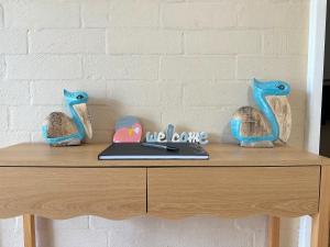 ein Schreibtisch mit zwei Vögeln und einem Laptop darauf in der Unterkunft Riverview Holiday Apartment 60 - Kalbarri WA in Kalbarri