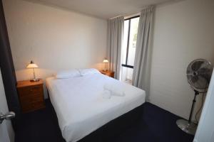 a bedroom with a white bed with a fan and a window at Riverview Holiday Apartment 93 - Kalbarri WA in Kalbarri
