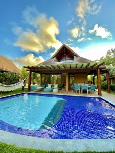 a swimming pool in front of a house at Bangalô com 3 suítes no Eco Resort na Praia dos Carneiros in Tamandaré